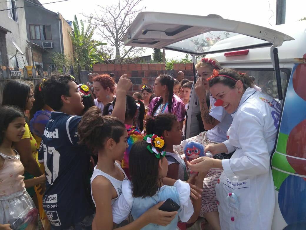 Doutora palhaça entregando brinquedos a crianças durante campanha assistencial